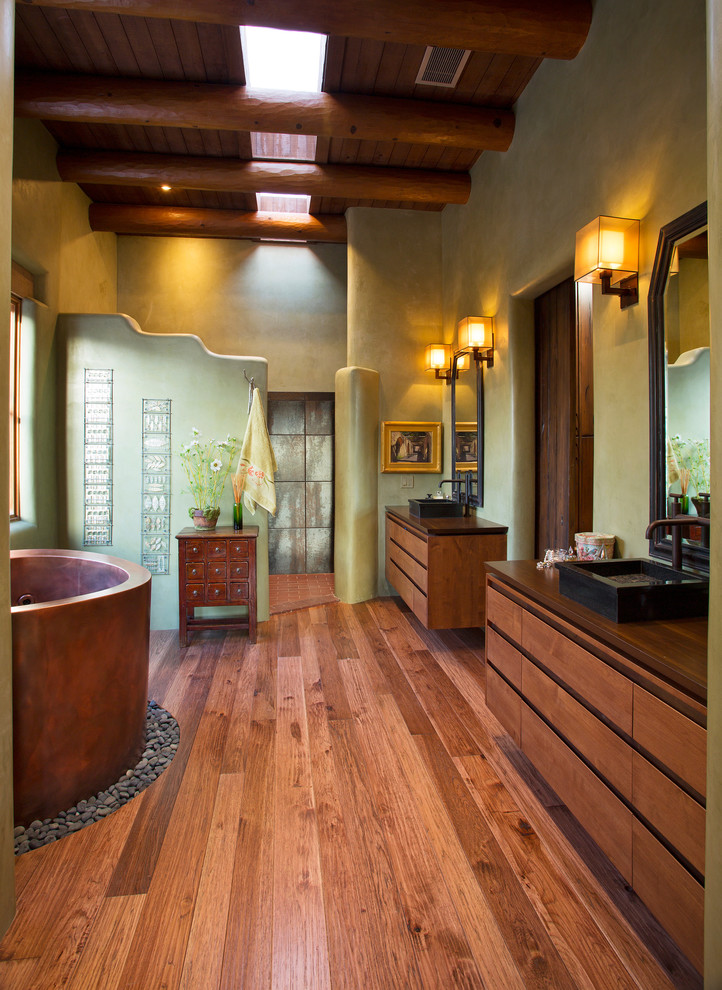 Réalisation d'une salle de bain principale sud-ouest américain en bois brun avec une vasque, un placard à porte plane, un plan de toilette en bois, un bain japonais, une douche ouverte, un mur vert, un sol en bois brun et aucune cabine.