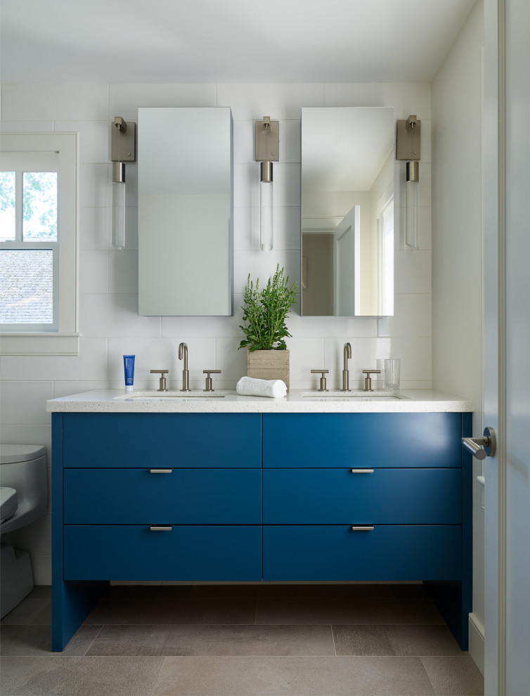 Foto på ett funkis vit badrum, med släta luckor, blå skåp, vit kakel, ett undermonterad handfat och grått golv