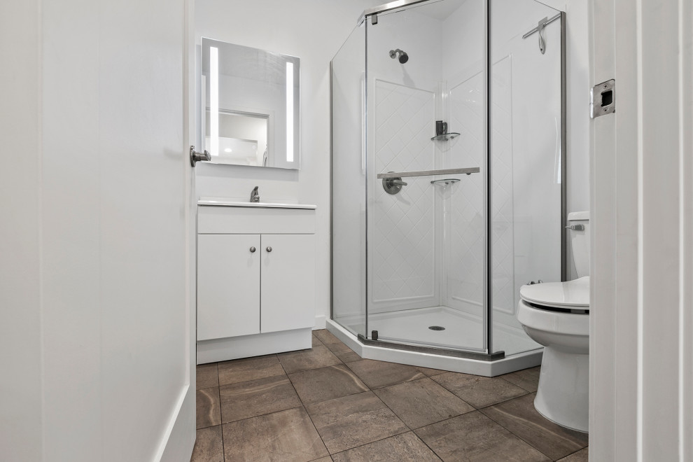 This is an example of a small modern bathroom in Los Angeles with flat-panel cabinets, white cabinets, a corner shower, a two-piece toilet, white tiles, porcelain tiles, white walls, cement flooring, a built-in sink, solid surface worktops, grey floors, a hinged door, white worktops, a single sink and a built in vanity unit.