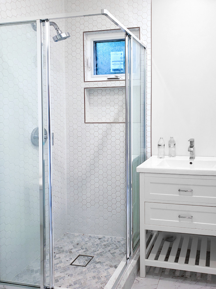 This is an example of a small country shower room bathroom in Los Angeles with shaker cabinets, white cabinets, a corner shower, a two-piece toilet, white tiles, porcelain tiles, white walls, marble flooring, an integrated sink, marble worktops, beige floors, a sliding door and white worktops.