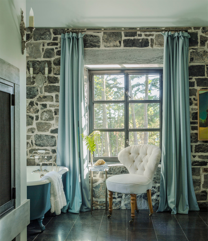 Imagen de cuarto de baño de estilo de casa de campo con bañera con patas, paredes multicolor, suelo marrón y piedra
