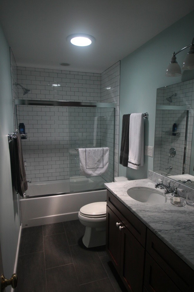 Bild på ett funkis badrum, med skåp i shakerstil, skåp i mörkt trä, en dusch/badkar-kombination, en toalettstol med separat cisternkåpa, blå väggar, skiffergolv, ett undermonterad handfat, marmorbänkskiva, ett badkar i en alkov och tunnelbanekakel
