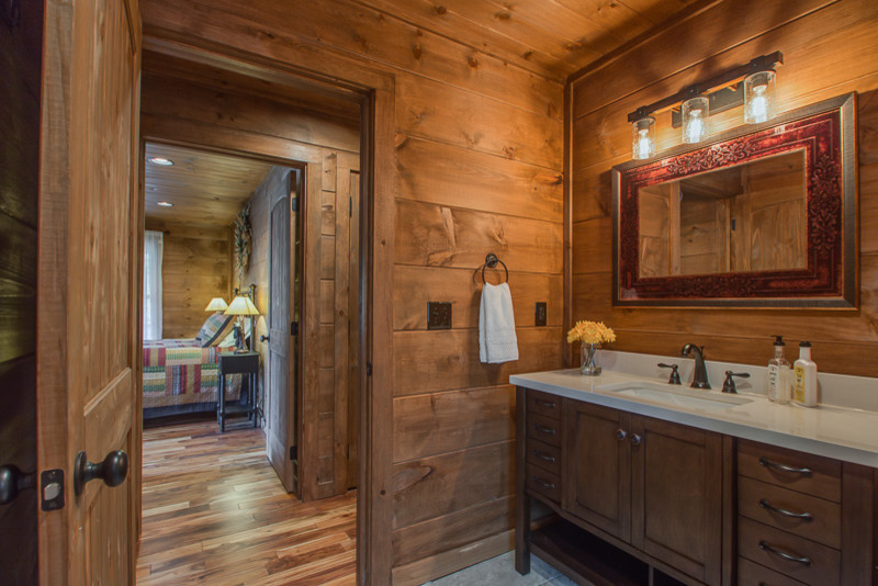 Photo of a small rustic family bathroom in Nashville with flat-panel cabinets, brown cabinets, a freestanding bath, a two-piece toilet, multi-coloured tiles, stone tiles, brown walls, ceramic flooring, a built-in sink, granite worktops and grey floors.