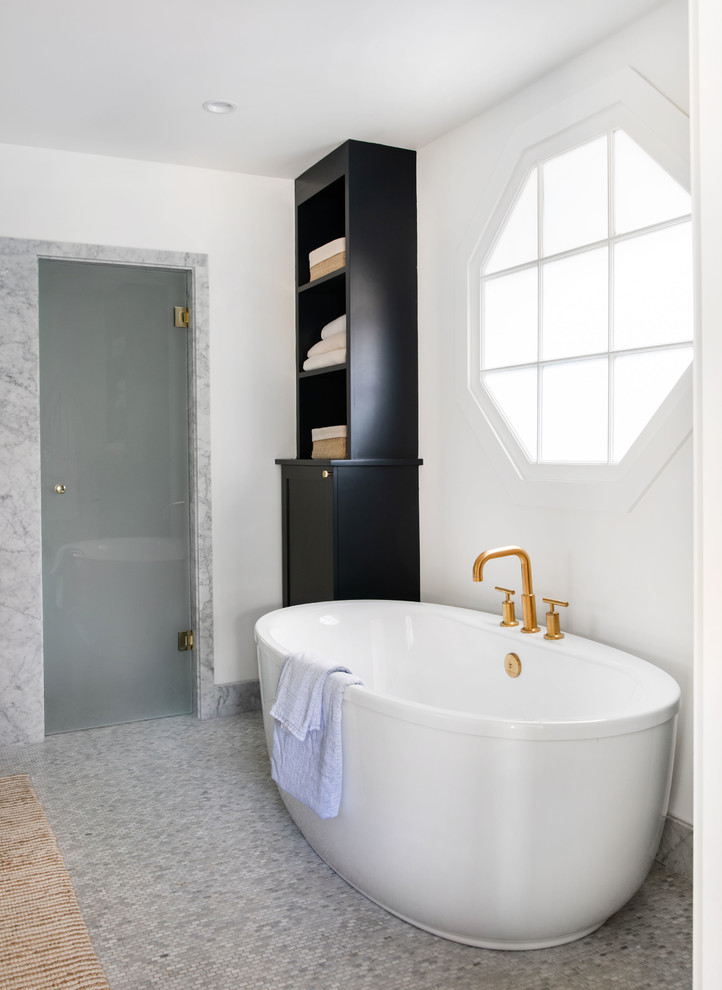 Photo of a large traditional ensuite bathroom in Los Angeles with shaker cabinets, black cabinets, a freestanding bath, a built-in shower, white walls, marble flooring, a submerged sink, marble worktops, grey floors, a hinged door and white worktops.