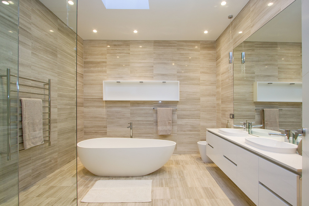 На фото: ванная комната в современном стиле с плоскими фасадами, белыми фасадами, отдельно стоящей ванной, бежевой плиткой, душевой кабиной, настольной раковиной и бежевым полом с