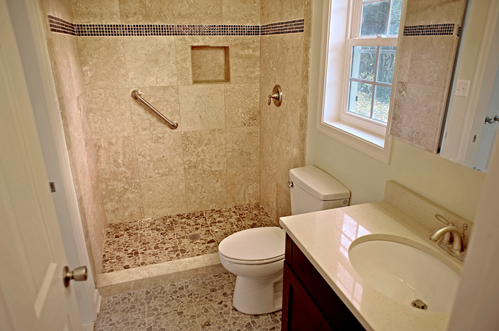 ワシントンD.C.にあるお手頃価格のトラディショナルスタイルのおしゃれな浴室 (壁付け型シンク、家具調キャビネット、茶色いキャビネット、珪岩の洗面台、オープン型シャワー、一体型トイレ	、ベージュのタイル、セラミックタイル) の写真