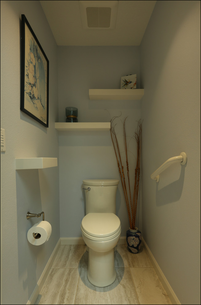 Cette photo montre un WC et toilettes chic de taille moyenne avec un placard à porte plane, des portes de placard blanches, un carrelage beige, un mur bleu, un sol en carrelage de céramique, une vasque, un plan de toilette en granite, un sol beige et un plan de toilette beige.