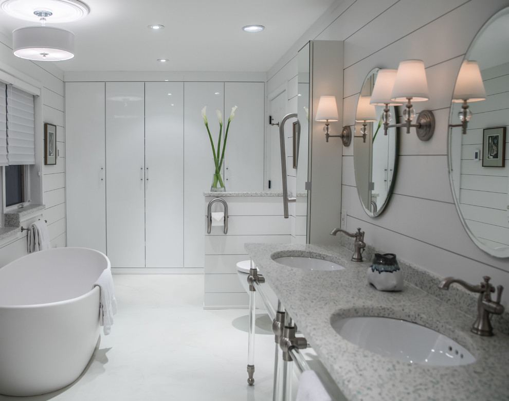 Foto på ett mellanstort lantligt en-suite badrum, med släta luckor, vita skåp, ett fristående badkar, en vägghängd toalettstol, vita väggar, betonggolv, ett undermonterad handfat, vitt golv och bänkskiva i terrazo