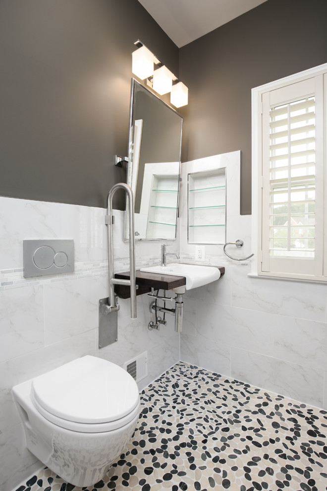 Cette image montre une petite salle d'eau minimaliste avec un lavabo posé, un plan de toilette en bois, une douche à l'italienne, WC suspendus, un carrelage multicolore, des carreaux de porcelaine, un mur gris et un sol en galet.