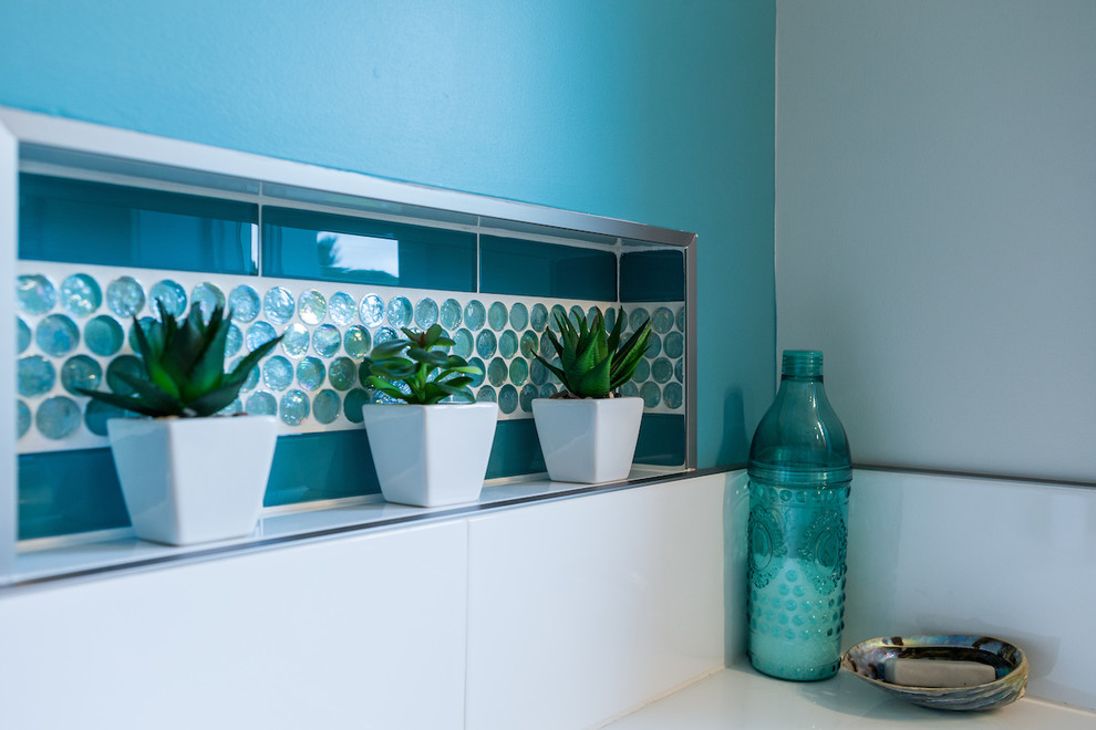 Пример оригинального дизайна: главная ванная комната среднего размера в стиле неоклассика (современная классика) с плоскими фасадами, серыми фасадами, угловой ванной, душем в нише, унитазом-моноблоком, синей плиткой, стеклянной плиткой, белыми стенами, полом из керамогранита, накладной раковиной, стеклянной столешницей, белым полом и душем с распашными дверями