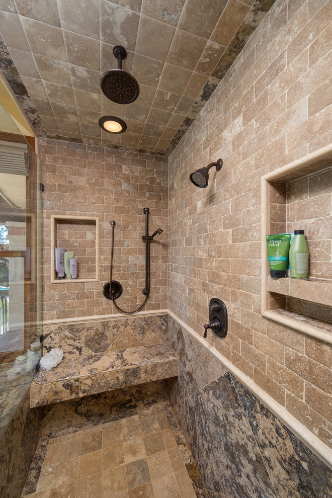 Cette photo montre une grande salle de bain principale chic en bois foncé avec un placard avec porte à panneau encastré, une baignoire d'angle, une douche d'angle, un carrelage marron, un carrelage de pierre, un mur beige, un sol en carrelage de porcelaine, un lavabo encastré et un plan de toilette en calcaire.
