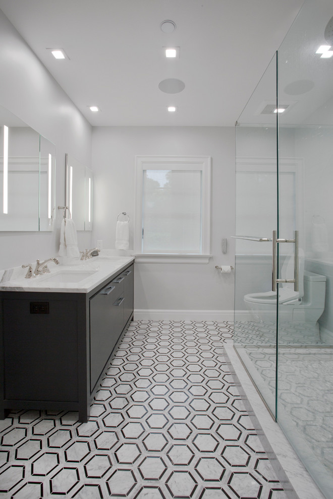This is an example of a large modern ensuite bathroom in New York with flat-panel cabinets, black cabinets, a corner shower, a one-piece toilet, white tiles, marble tiles, white walls, ceramic flooring, a built-in sink, marble worktops, multi-coloured floors, a hinged door and white worktops.