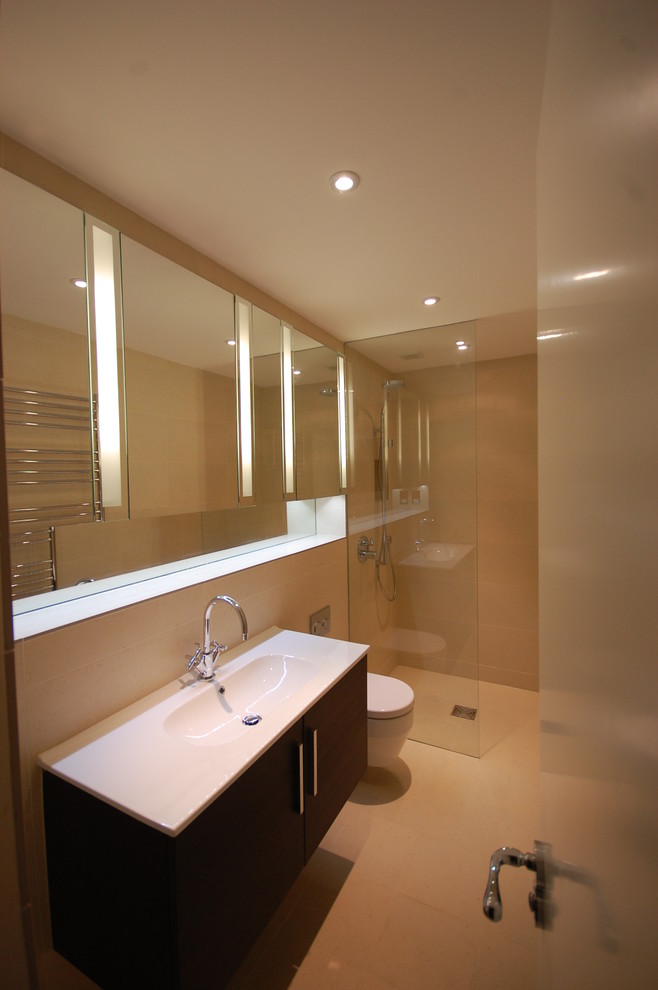 Design ideas for a small contemporary shower room bathroom in London with a built-in sink, flat-panel cabinets, medium wood cabinets, a built-in bath, a built-in shower, a wall mounted toilet, beige tiles, porcelain tiles, beige walls and porcelain flooring.