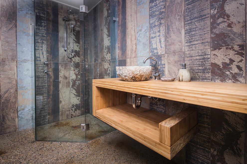 Ejemplo de cuarto de baño urbano pequeño con ducha esquinera, suelo de cemento, lavabo sobreencimera, encimera de madera y encimeras marrones