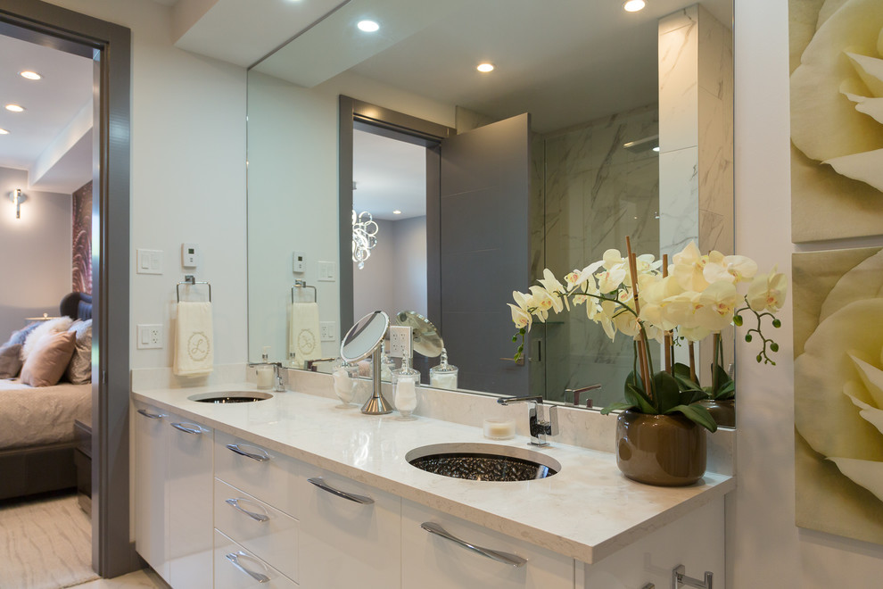 This is an example of a medium sized modern ensuite bathroom in Vancouver with flat-panel cabinets, yellow cabinets, a one-piece toilet, stone slabs, white walls, marble flooring, a submerged sink, quartz worktops, white floors and white worktops.