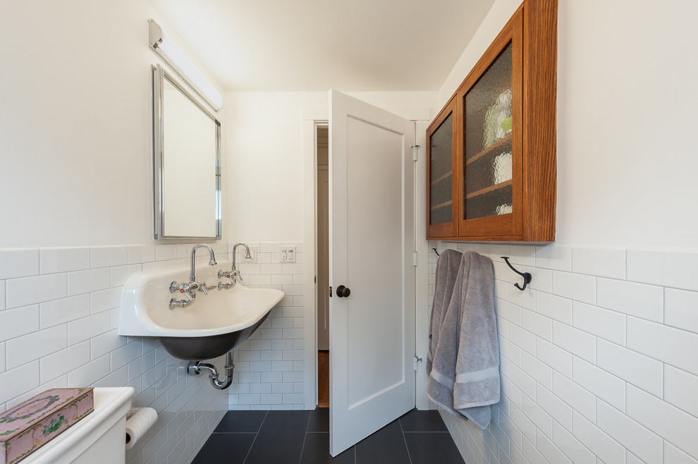 Large eclectic shower room bathroom in San Francisco with an alcove bath, a shower/bath combination, a one-piece toilet, white tiles, metro tiles, white walls, porcelain flooring, a trough sink, black floors and a shower curtain.