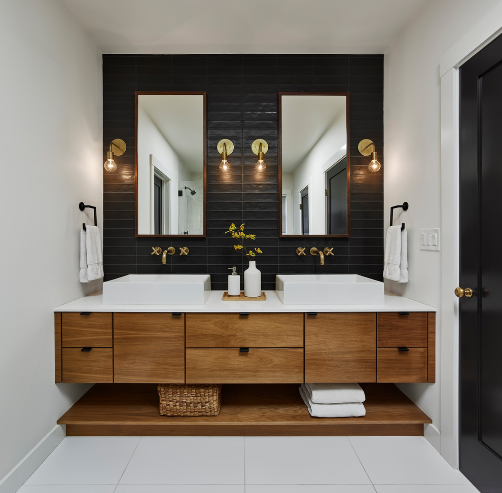 Aménagement d'une salle de bain contemporaine en bois brun avec un placard à porte plane, un carrelage noir, un mur blanc, une vasque, un sol blanc et un plan de toilette blanc.