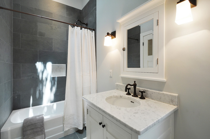 На фото: большая ванная комната в стиле неоклассика (современная классика) с врезной раковиной, белыми фасадами, ванной в нише, белыми стенами, фасадами в стиле шейкер, душем в нише, серой плиткой, каменной плиткой, полом из сланца, мраморной столешницей, серым полом и шторкой для ванной