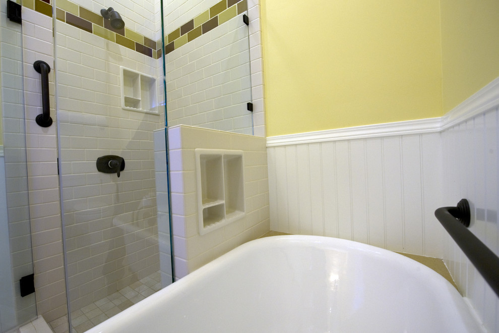На фото: ванная комната в классическом стиле с фасадами в стиле шейкер, фасадами цвета дерева среднего тона, ванной на ножках, угловым душем, белой плиткой, плиткой кабанчик, желтыми стенами, врезной раковиной, душем с распашными дверями и бежевой столешницей