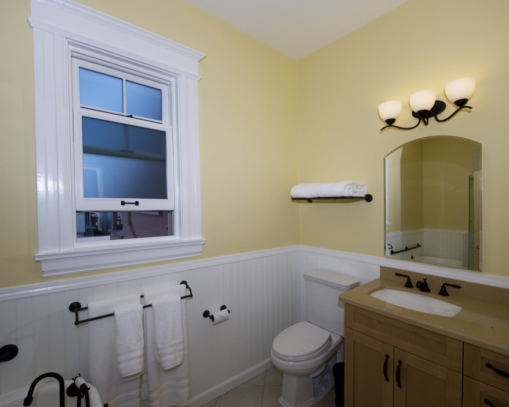 サンフランシスコにあるトラディショナルスタイルのおしゃれな浴室 (シェーカースタイル扉のキャビネット、中間色木目調キャビネット、黄色い壁、アンダーカウンター洗面器、ベージュのカウンター) の写真