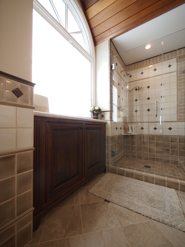 Medium sized traditional ensuite bathroom in San Francisco with raised-panel cabinets, dark wood cabinets, an alcove shower, a two-piece toilet, beige tiles, brown tiles, white tiles, cement tiles, beige walls, ceramic flooring, a submerged sink, marble worktops, brown floors and a hinged door.