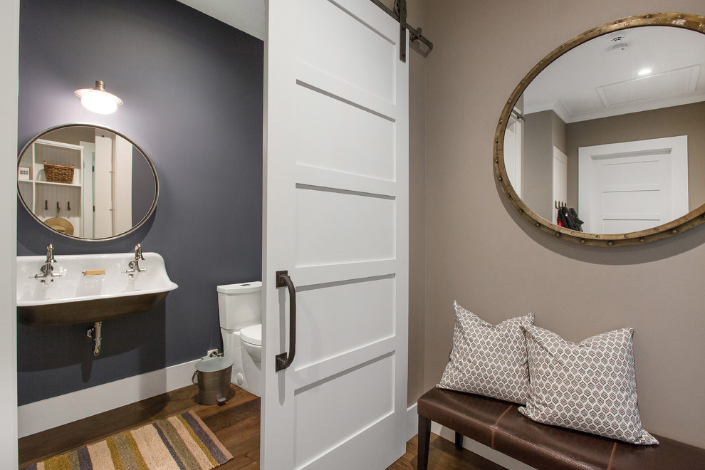 Imagen de cuarto de baño campestre pequeño con paredes azules, suelo de madera en tonos medios, sanitario de dos piezas y lavabo de seno grande