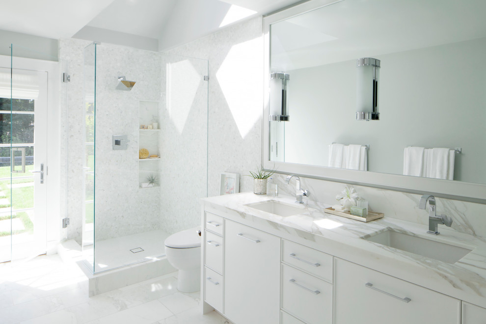 Exemple d'une grande salle de bain tendance pour enfant avec des portes de placard blanches, une douche d'angle, WC à poser, un carrelage blanc, un carrelage de pierre, un mur blanc, un sol en marbre, un lavabo encastré, un plan de toilette en marbre et un placard à porte affleurante.