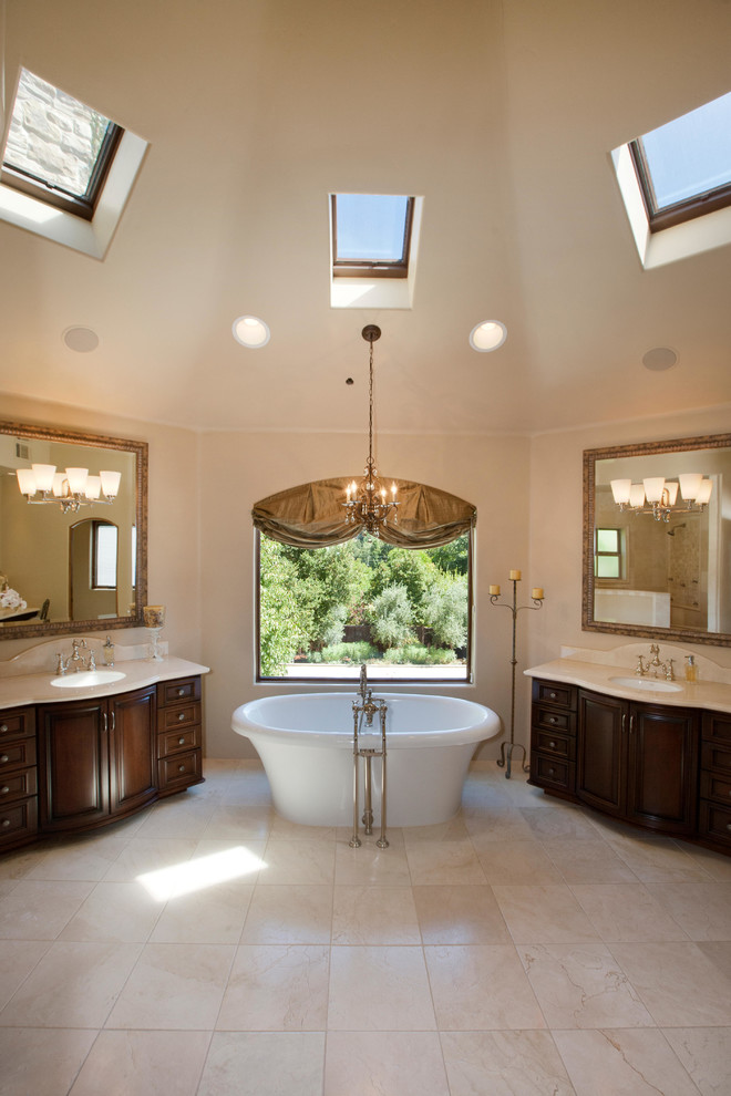 Inspiration for a large traditional ensuite bathroom in San Francisco with freestanding cabinets, dark wood cabinets, a freestanding bath, beige walls, limestone flooring, a submerged sink and a walk-in shower.