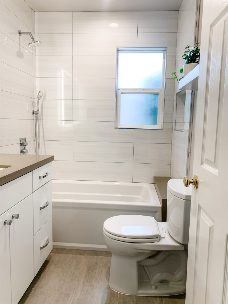 На фото: маленькая ванная комната в скандинавском стиле с плоскими фасадами, белыми фасадами, ванной в нише, душем над ванной, унитазом-моноблоком, белой плиткой, керамогранитной плиткой, серыми стенами, полом из керамогранита, врезной раковиной, столешницей из искусственного кварца, бежевым полом, шторкой для ванной и бежевой столешницей для на участке и в саду