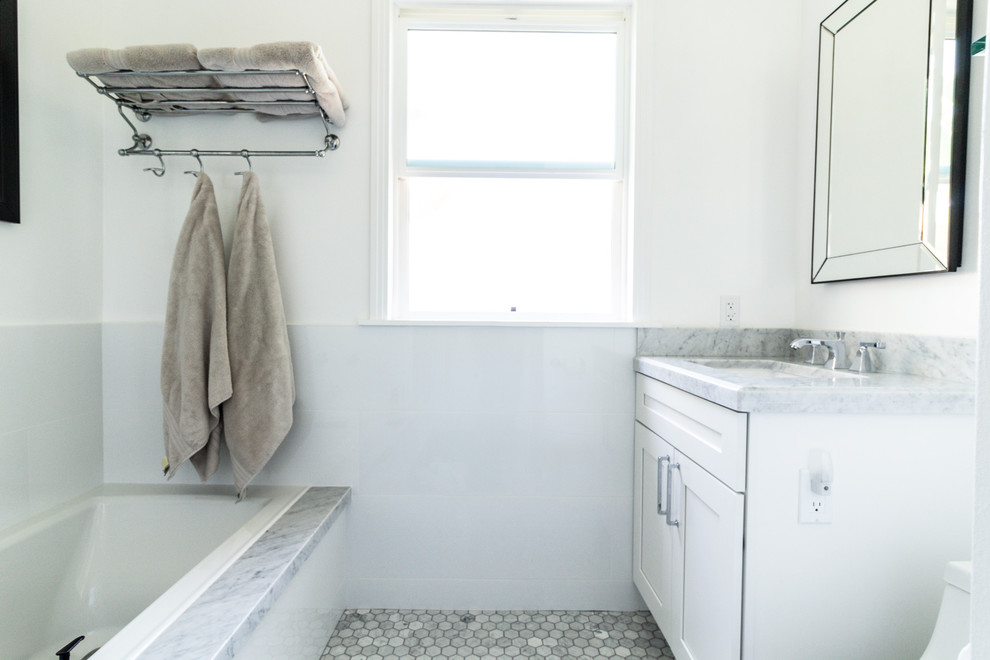 Bild på ett litet funkis badrum med dusch, med vita väggar, marmorgolv, vitt golv, en toalettstol med hel cisternkåpa, ett undermonterad handfat, skåp i shakerstil, vita skåp, ett badkar i en alkov, marmorbänkskiva, en hörndusch och dusch med gångjärnsdörr