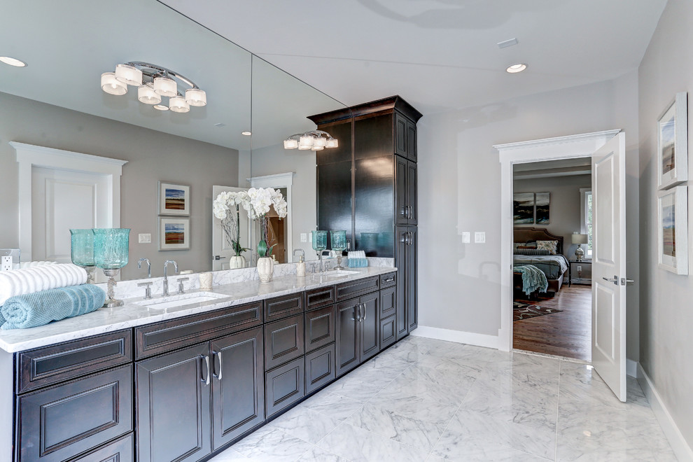 Photo of a medium sized mediterranean ensuite bathroom in DC Metro with louvered cabinets, brown cabinets, a freestanding bath, an alcove shower, a two-piece toilet, grey tiles, marble tiles, grey walls, marble flooring, a submerged sink, engineered stone worktops, white floors and a hinged door.