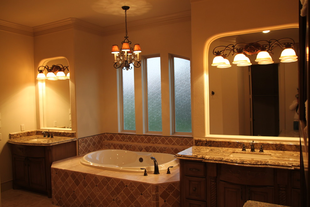 Design ideas for a large mediterranean ensuite bathroom in Houston with recessed-panel cabinets, beige cabinets, a built-in bath, a built-in shower, a one-piece toilet, beige tiles, stone tiles, beige walls, travertine flooring, a submerged sink and granite worktops.