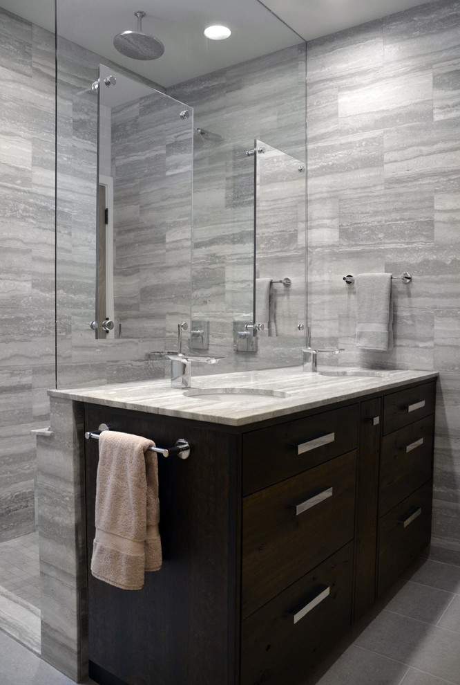 Photo of a large contemporary ensuite bathroom in Chicago with a submerged sink, flat-panel cabinets, dark wood cabinets, a built-in shower, grey tiles, marble worktops, a one-piece toilet, stone tiles, grey walls, porcelain flooring and grey worktops.