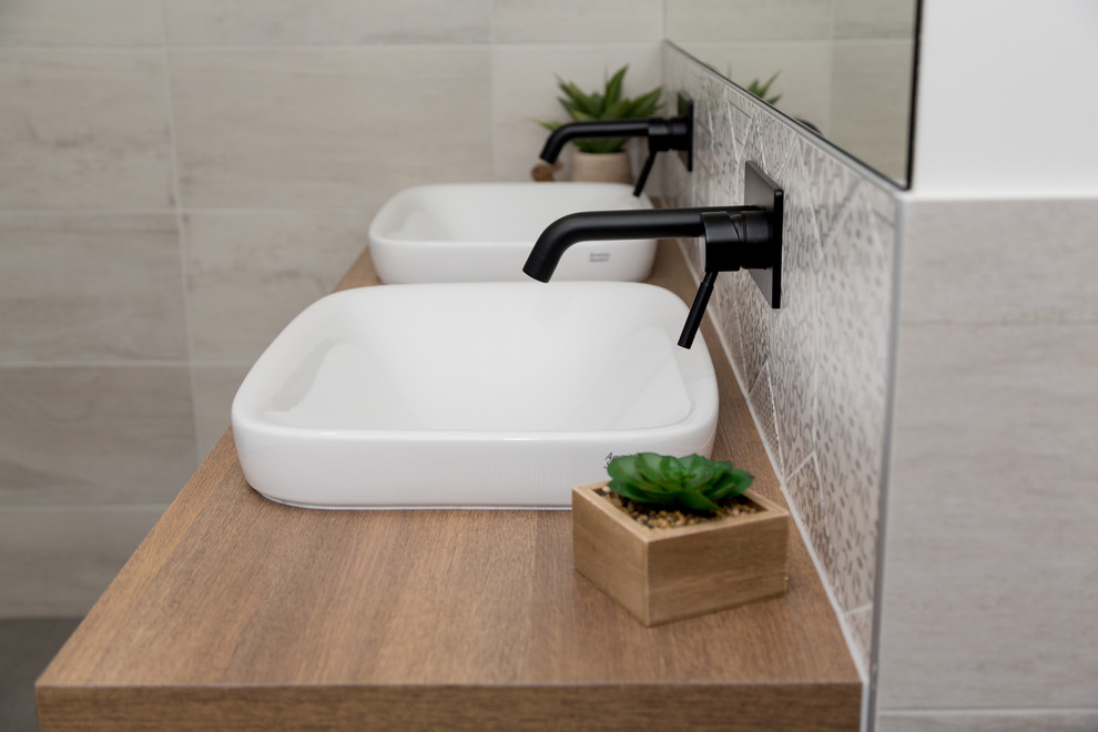 На фото: ванная комната в скандинавском стиле с плоскими фасадами, фасадами цвета дерева среднего тона, белой плиткой, керамической плиткой и столешницей из ламината с