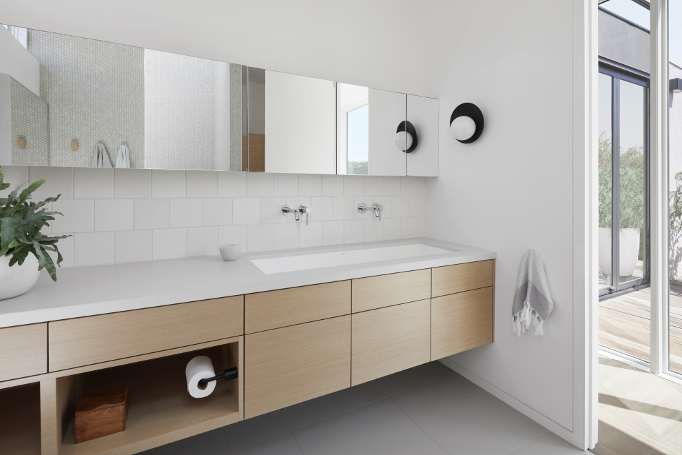 Idée de décoration pour une salle de bain minimaliste en bois clair avec un placard à porte plane, un mur blanc, un lavabo encastré, un sol gris et un plan de toilette blanc.