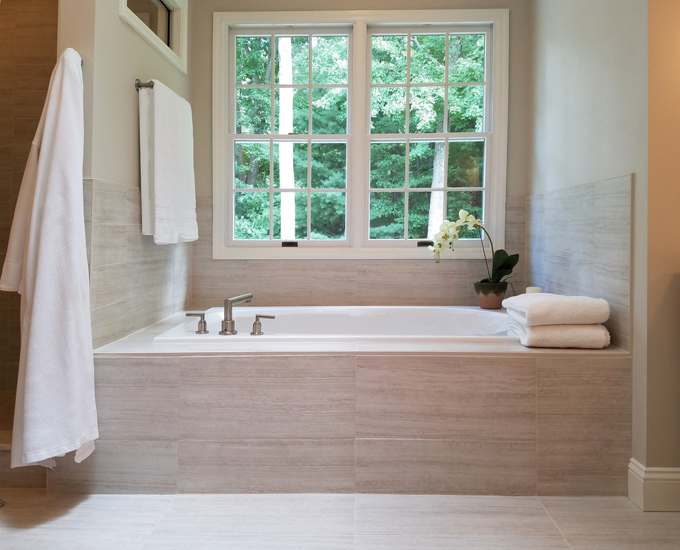 Cette photo montre une salle de bain principale tendance de taille moyenne avec une baignoire posée, un carrelage beige, des carreaux de porcelaine, un mur beige, un sol en carrelage de porcelaine et un sol beige.