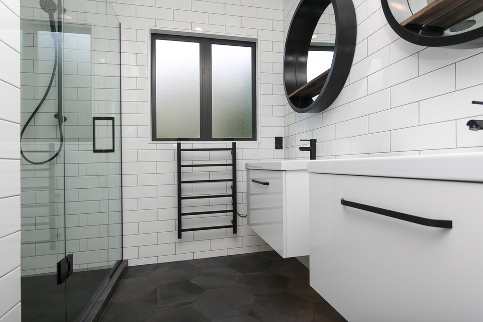 Inredning av ett modernt mellanstort en-suite badrum, med en dusch i en alkov, en toalettstol med hel cisternkåpa, vit kakel, tunnelbanekakel, vita väggar, klinkergolv i porslin, ett väggmonterat handfat, grått golv och dusch med gångjärnsdörr