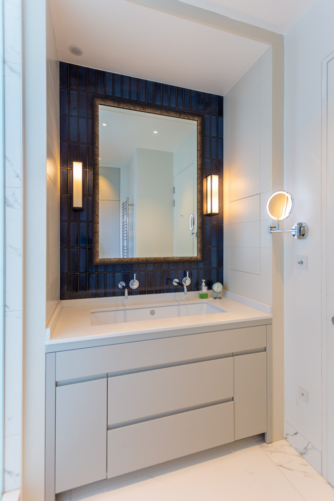 Imagen de cuarto de baño actual con armarios con paneles lisos, puertas de armario blancas, baldosas y/o azulejos azules, paredes blancas, lavabo bajoencimera, suelo blanco y encimeras blancas