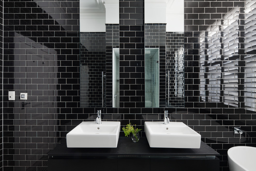Modern inredning av ett badrum, med ett fristående badkar, en dusch i en alkov, svart kakel och ett fristående handfat