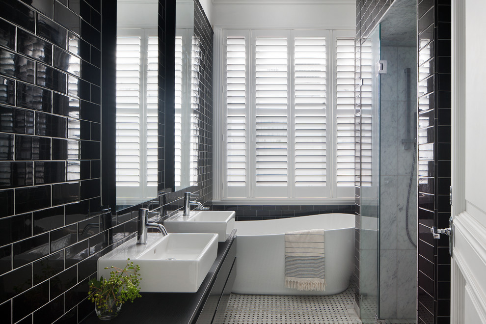 Cette image montre une douche en alcôve principale design de taille moyenne avec des portes de placard noires, une baignoire indépendante, un carrelage noir et blanc, un mur noir, un sol en marbre et une vasque.