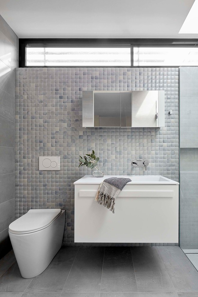 На фото: маленькая ванная комната в современном стиле с плоскими фасадами, белыми фасадами, унитазом-моноблоком, синей плиткой, плиткой мозаикой, столешницей из искусственного камня и белой столешницей для на участке и в саду с