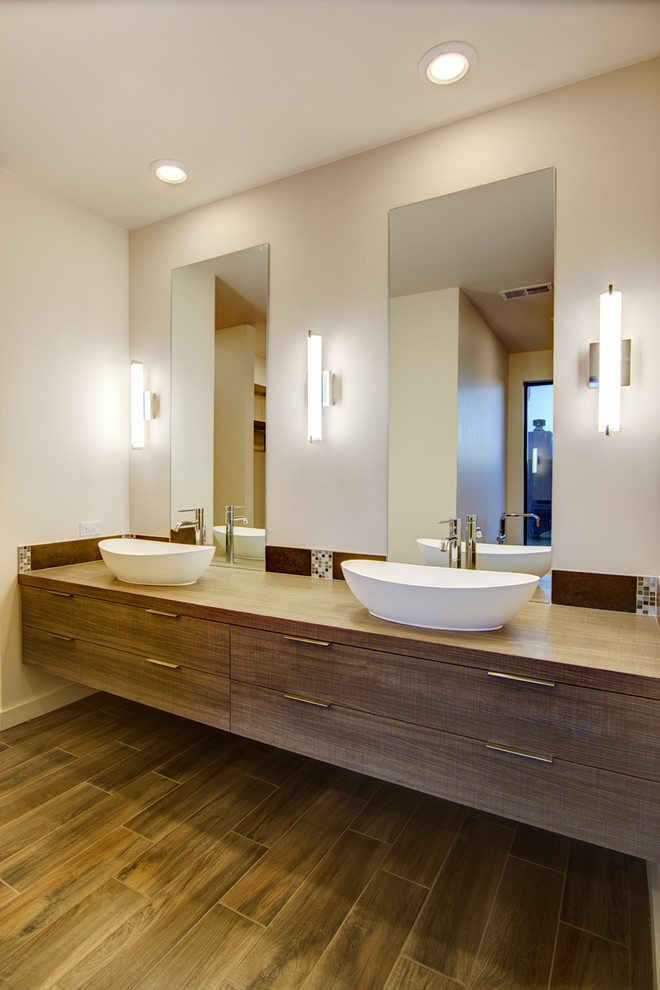 Example of a mid-sized trendy master medium tone wood floor walk-in shower design in Albuquerque with flat-panel cabinets, medium tone wood cabinets, a two-piece toilet, a vessel sink, wood countertops and white walls