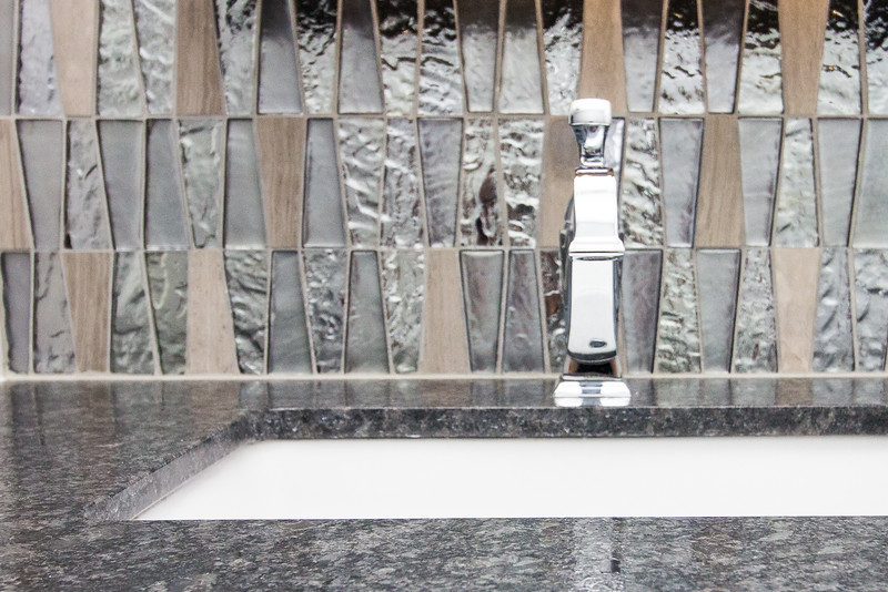 Cette image montre une petite salle d'eau minimaliste avec un placard à porte shaker, des portes de placard blanches, une baignoire en alcôve, un combiné douche/baignoire, WC séparés, un carrelage multicolore, des carreaux de porcelaine, un mur noir, un sol en carrelage de porcelaine, un lavabo encastré, un plan de toilette en granite et un sol gris.