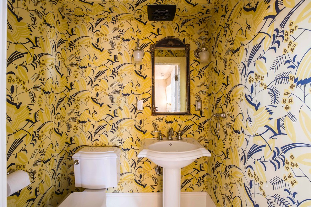 Immagine di un piccolo bagno di servizio tradizionale con WC a due pezzi, pareti gialle, lavabo a colonna e carta da parati