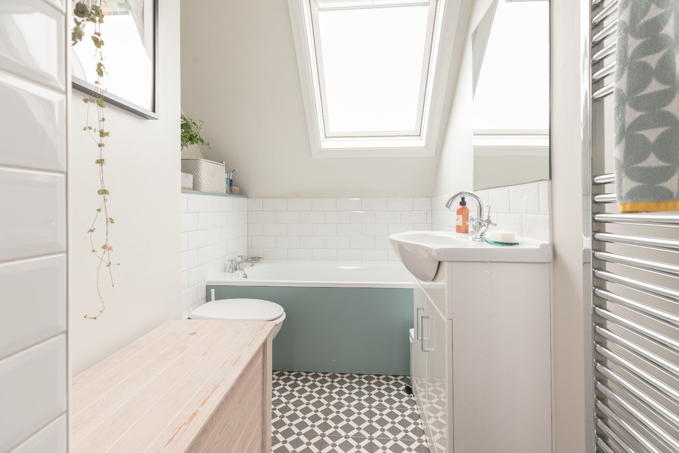 Bild på ett funkis badrum, med vit kakel, keramikplattor, klinkergolv i porslin, släta luckor, vita skåp, ett platsbyggt badkar, vita väggar, ett konsol handfat och grått golv