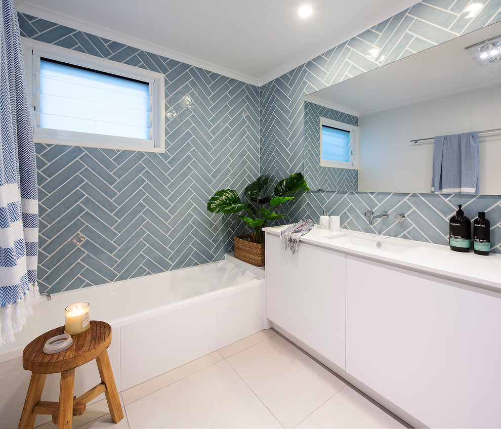 Идея дизайна: ванная комната среднего размера в морском стиле с белыми фасадами, синей плиткой, керамической плиткой, полом из керамической плитки, врезной раковиной, столешницей из искусственного кварца, бежевым полом, белой столешницей, плоскими фасадами, ванной в нише, синими стенами и душевой кабиной