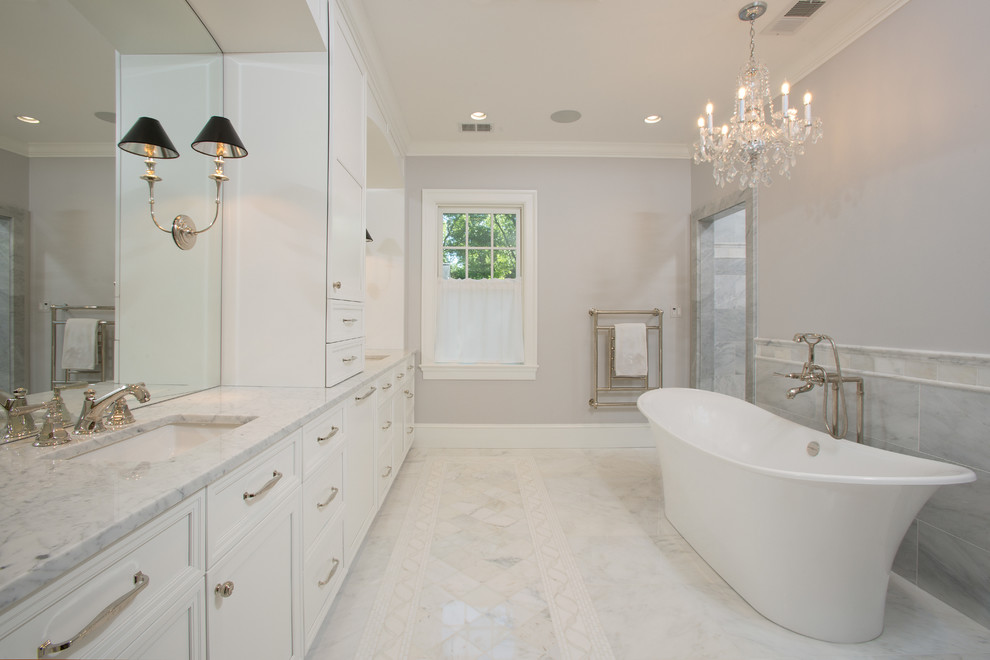 This is an example of an expansive traditional ensuite bathroom in DC Metro with recessed-panel cabinets, white cabinets, grey walls, marble flooring, a submerged sink, marble worktops, white floors, a freestanding bath, grey tiles and marble tiles.