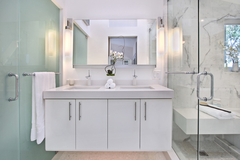 Modern inredning av ett vit vitt en-suite badrum, med släta luckor, vita skåp, ett badkar i en alkov, en dubbeldusch, vit kakel, marmorkakel, vita väggar, klinkergolv i porslin, ett undermonterad handfat, bänkskiva i akrylsten, vitt golv och dusch med gångjärnsdörr