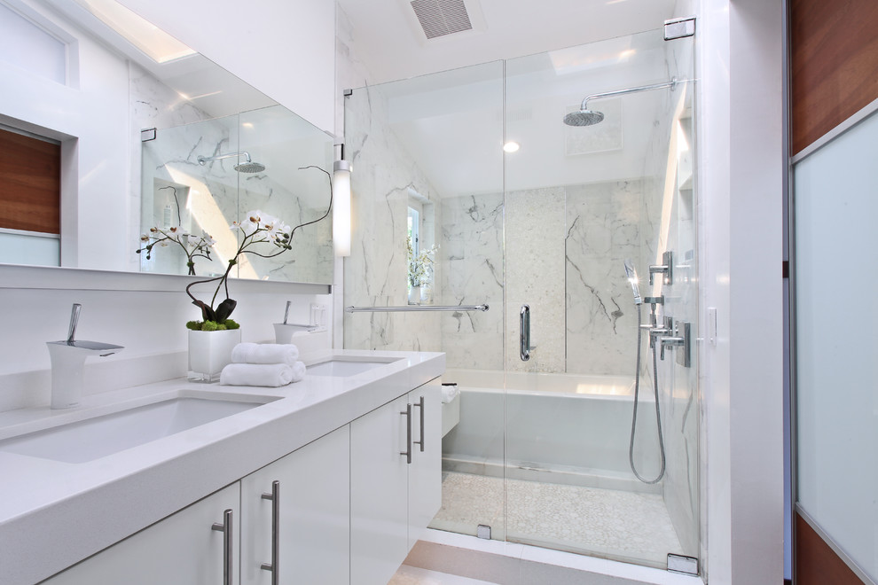Свежая идея для дизайна: главная ванная комната в современном стиле с плоскими фасадами, белыми фасадами, ванной в нише, двойным душем, унитазом-моноблоком, белой плиткой, мраморной плиткой, белыми стенами, полом из керамогранита, врезной раковиной, столешницей из искусственного камня, белым полом, душем с распашными дверями и белой столешницей - отличное фото интерьера