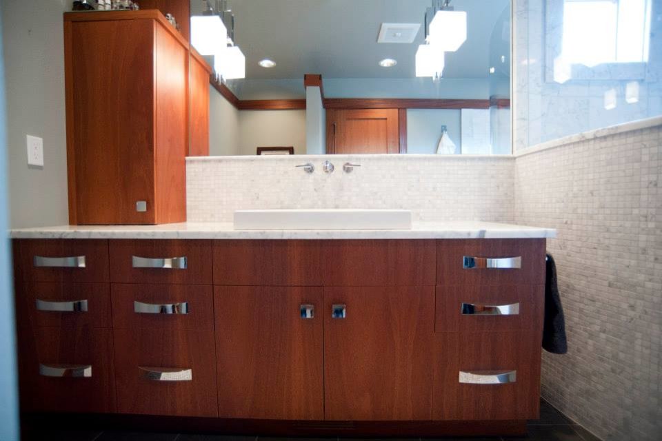 Cette image montre une salle de bain principale design en bois brun de taille moyenne avec une vasque, un placard à porte plane, un plan de toilette en marbre, une douche ouverte, WC à poser, un carrelage gris et un mur gris.
